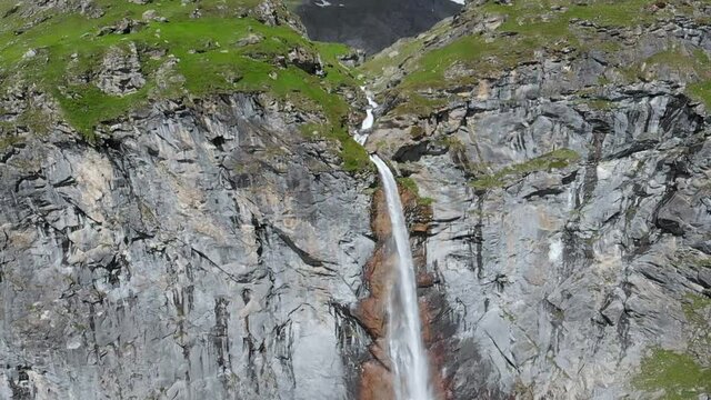 Aerial slow motion: drone flying over scenic high waterfall, mountain stream falling from tall rocky cliff on the italian Alps. Pis waterfall near Torino, Piedmont, Italy