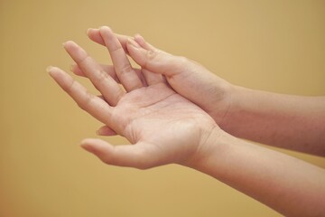 Close up of a hand using hand sanitizer with yellow backgorund.