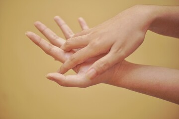 Close up of a hand using hand sanitizer with yellow backgorund.