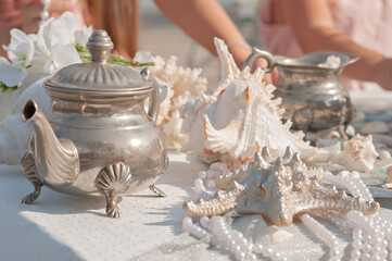 Decoration of holidays, events and weddings in a marine style. On the table are beautiful corals, a variety of shells, pearls, starfish. Unusual interior design of houses apartments. Romantic dinner
