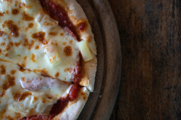 Viewed from above of pizza flavored with ham, tomato sauce and mushroom. Ready to eat. Placed on a round wooden floor