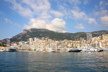 Fototapeta na wymiar View from the Mediteranean sea of the Principality of Monaco, and Monte Carlo, with dense skyscrappers , the marina, yachts, palace & casino. 