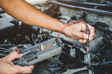 Auto mechanic using measuring equipment tool for fix checking car battery. Concepts of Old car repair service and insurance.