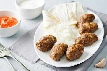 Minced meat sausage with onion, sour cream, pita and red bell pepper relish