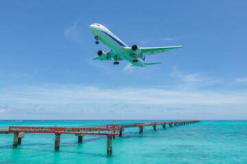 Fototapeta na wymiar Landing airplane on emelardgreen ocean in summer