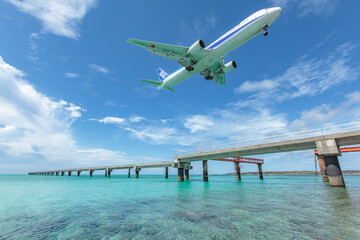 Landing airplane on emelardgreen ocean in summer