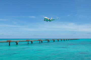 Landing airplane on emelardgreen ocean in summer