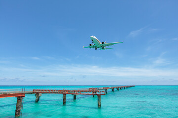 Fototapeta na wymiar Landing airplane on emelardgreen ocean in summer