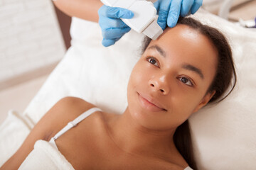 Young African woman getting facial treatment