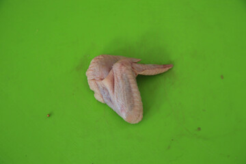 Raw chicken wings with a green background