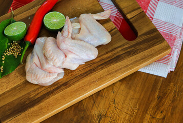 Raw chicken wings with herbs and a wooden plank background