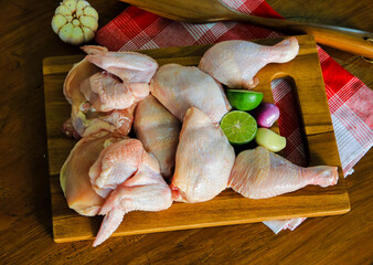 Raw chicken with herbs and a wooden plank background