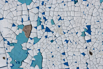Peeling paint on the wall. Old concrete wall with cracked flaking paint. Weathered rough painted surface with patterns of cracks and peeling. Grunge texture for background and design. High resolution.