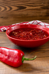 Ukrainian beetroot red hot borsch with red pepper on a brown wooden table. Top-side view