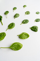 Fresh green spinach leaves on a white table. Healthy vegetable diet food. Vertical. Top view. 