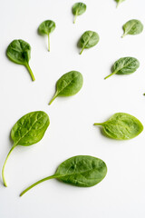 Fresh green spinach leaves on a white table. Healthy vegetable diet food. Vertical. Top view. Close-up