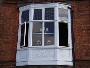 A close up of an upper floor bay window in an old English brick house.
