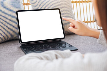 Mockup image of a woman using and pointing finger at tablet pc with blank desktop white screen as a computer pc on sofa at home