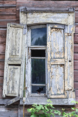 Window of an old wooden house with half-open shutters