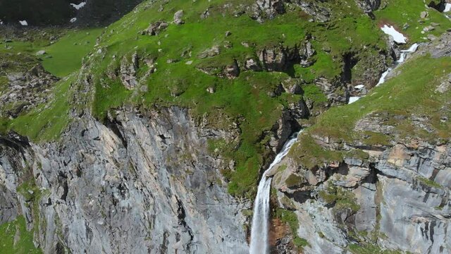 Aerial: drone flying over scenic high waterfall lush green valley and mountain stream on the italian Alps. Tourism destination hiking outdoors activity. Pis waterfall near Torino, Piedmont, Italy