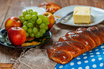 Wicker bun, lemon, apples, green grapes and butter on a wooden table. Jewish holiday Shavuot.