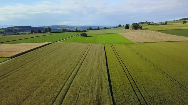 Vue a&eacute;rienne par drone au-dessus de la campagne ensoleill&eacute;e et de ses champs dans le canton de Vaud en Suisse romande le vol est calme avec un vol en crabe horizontalement &agrave; droite