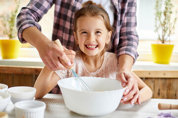 Mother teaching daughter prepare dough together in kitchen