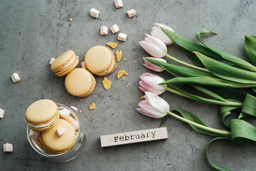 Flat Lay Background of Fresh Tulips, Yellow French Macarons and Calendar February on the Table