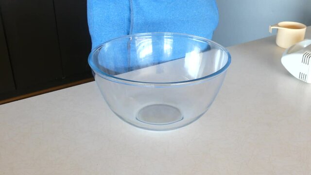 Man standing in front of an empty bowl getting ready to bake something in a blue jumper