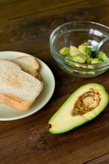 Fried bread for toasts and avocado for breakfast in the morning on brown woodwn table.  Vretical