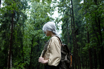Fototapeta na wymiar Blonde woman with backpack in rainy day in forest