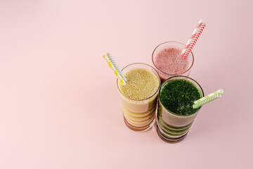 Flat Lay of Three Different Colored Smoothie Cocktails on Pink Background