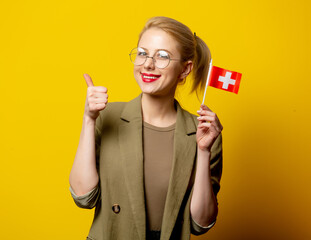 Style blonde woman in jacket with Swiss flag on yellow background