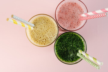 Flat Lay of Three Different Colored Smoothie Cocktails on Pink Background