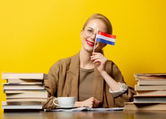blonde woman with flag of Netherlands and books on yellow background