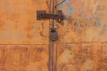 rusty old metal door locked with a metal padlock.  Grunge style .