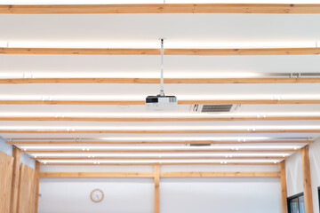 the projector is hanged on to seminar hall ceiling. It's standing by for lighting out the presentation from the speaker.