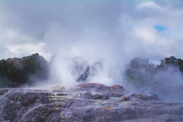 Active geysers erupting above rocks