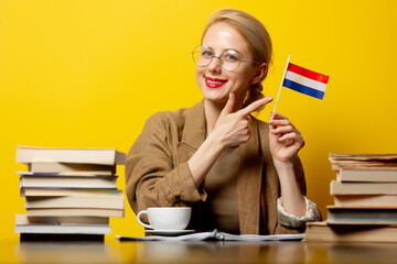 blonde woman with flag of Netherlands and books on yellow background