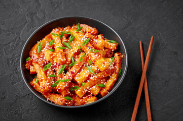 Honey Chilli Potato or Schezwan Aloo in black bowl on dark slate table top. Chilli Potatoes is indo-chinese cuisine dish. Authentic asian food. Indian meal.