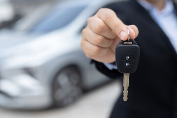 The staff holds the new car keys and offers special interest promotions to customers at the showroom.