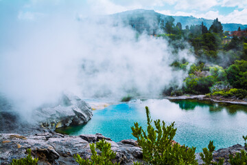 Thick steam hovering over turquoise water of a geothermal pool in the mountains