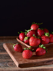 Strawberry in a plate on a wooden background.
