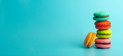 Colored macaroon cookies on a blue banner background. Bright festive pastries, desserts and sweets. Baking background