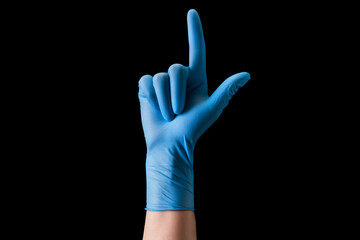 Doctor's hand in sterile medical gloves pointing up isolated on black