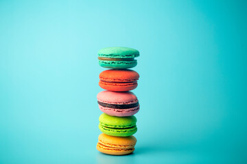 Colored macaroon (macarons) cookies on a blue background. Bright festive pastries, desserts and sweets. Baking background