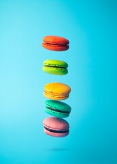 Flying Colored macaroon cookies on a blue background. Bright festive pastries, desserts and sweets. Baking background