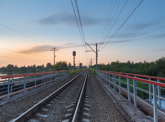Fototapeta na wymiar Railroad tracks on the bridge by the countryside in the evening
