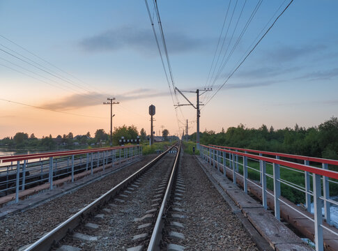 Railroad tracks on the bridge by the countryside in the evening