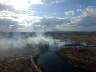 The smoke from the burning of dry grass (drone image).Local residents set fire to the grass specifically. Small animals are bending. Local features and habits.  Near Kiev,Ukraine
